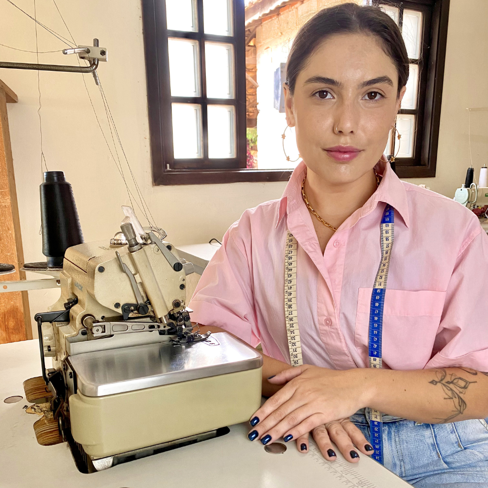 Natalia Matos ao lado da máquina de costura desenvolvendo peças LezAnis